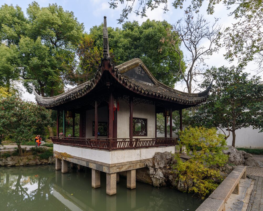 Traditional pavilion with upturned eaves beside a pond in the Humble Administrator's Garden, Suzhou