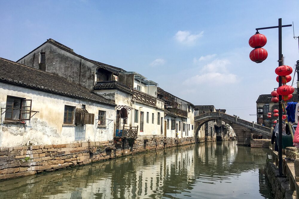 Stone bridge over the Shantang canal in Suzhou with red lanterns and old houses along the water